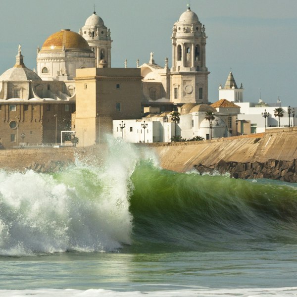 a large wave is breaking in front of a building
