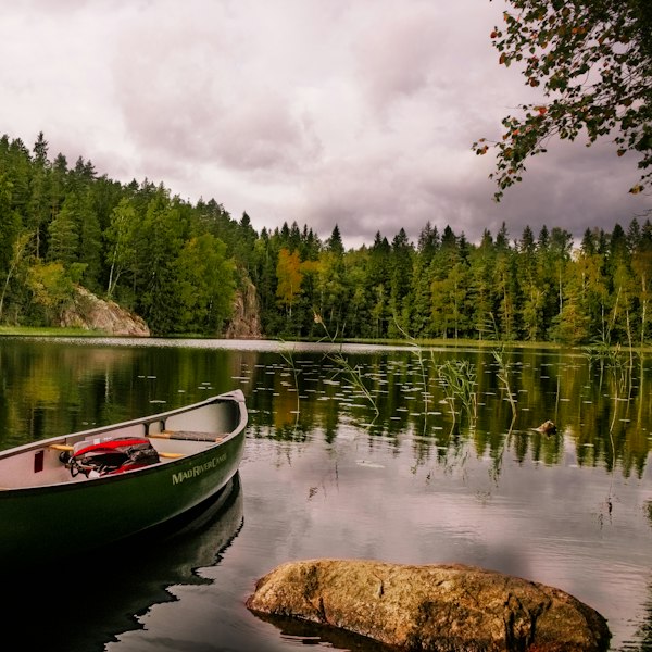 red and white canoe on lake near green trees under white clouds during daytime